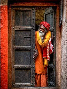 Painting of a sadhu in saffron robes at a carved wooden door in Banaras