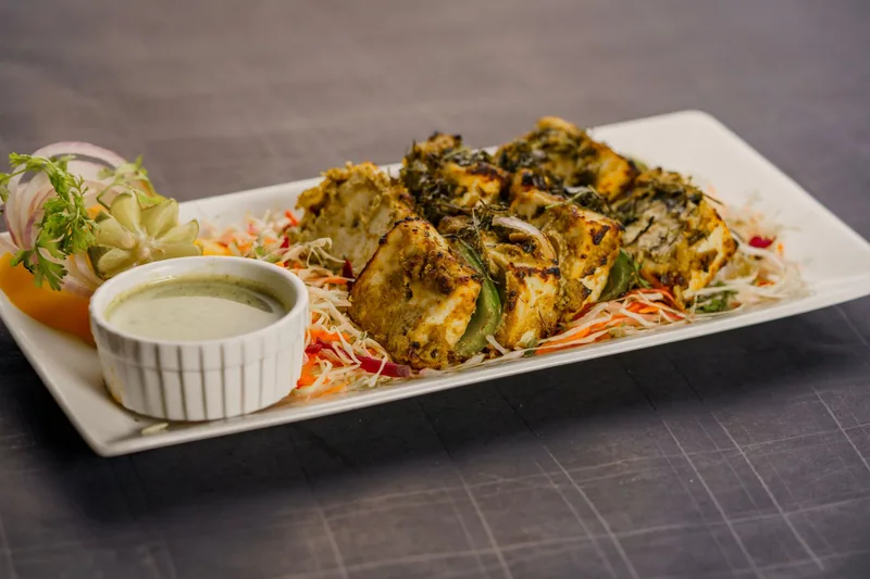 Paneer tikka and chaat plated on a dark slate surface