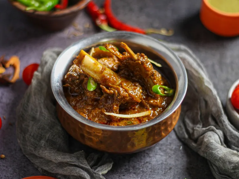 Bone-in goat curry served on a tawa